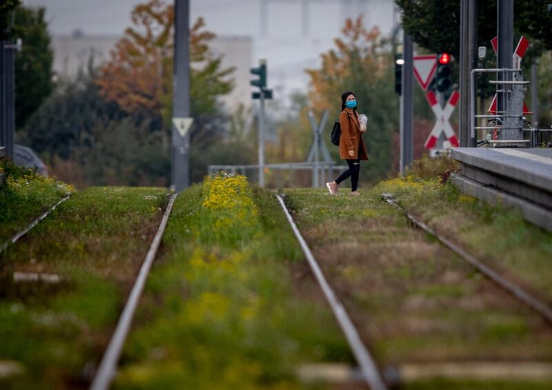 A woman with face mask crosses the rails near a subway station in Frankfurt, Germany. AP Photo