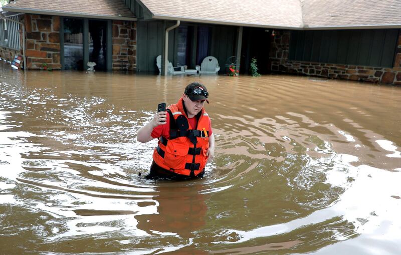 Tulsa County Sheriff's Deputy Miranda Munson makes her way back to a fan boat after checking a flooded house for occupants in the Town and Country neighborhood in Sand Springs, Oklahoma. Tulsa World via AP