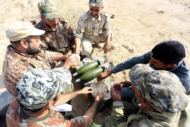 epa06144382 Members of Iraqi Shiite militia Imam Ali Brigades, which belongs to Shiite Popular Mobilization Forces, take rest during a live ammunition training exercise in Najaf city, southern Iraq, 14 August 2017.  Iraqi Prime Minister Haider al-Abadi declared that Shiite Popular Mobilization Forces will continue to battle the Islamic State group (IS) and will take part in Tal-Afar battle despite from calls to prevent Shiite militias from participating in the battle.  EPA/KHIDER ABBAS