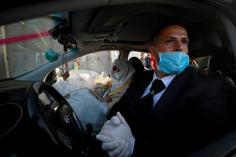 A Palestinian groom, Rafeh Qassim, wears a mask as he sits in a car with his bride on their wedding day amid concerns about the spread of the coronavirus disease (COVID-19), in Ramallah in the Israeli-occupied West Bank April 18, 2020. REUTERS/Mohamad Torokman TPX IMAGES OF THE DAY