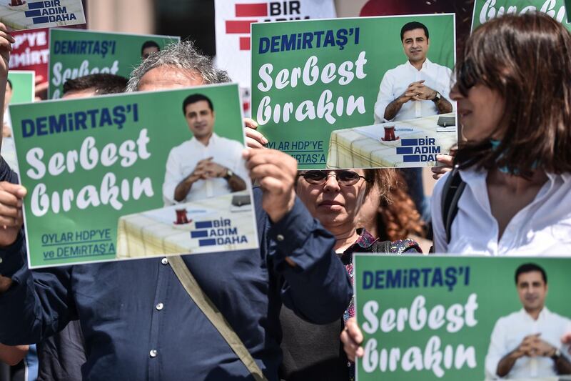 Supporters of the Peoples' Democratic Party (HDP) hold placards reading "Free Demirtas" in front of Istanbul's Courthouse on May 21, 2018, to demand the release of Pro-Kurdish party leader Selahattin Demirtas who is currently in a Turkish jail. Turkey's jailed former pro-Kurdish party leader Selahattin Demirtas, 45, who is running against the Turkish President in the June 24 polls despite being held in jail for the last one-and-a-half years, lambasted the "unfairness" of his campaign conditions, but said he was ready to rally voters from prison. / AFP / OZAN KOSE

