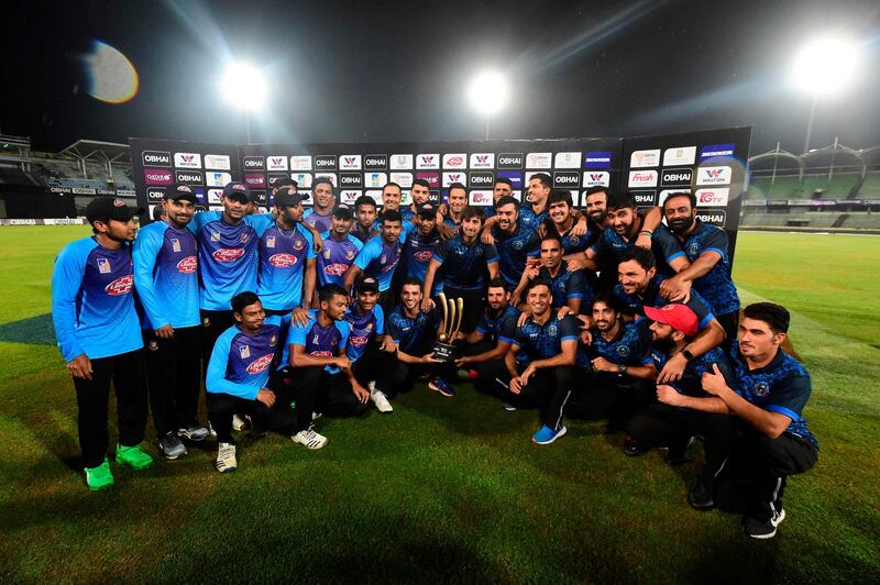 Bangladesh and Afghanistan cricketers pose for a photo with the tournament trophy after the match was abandoned for rainfall during the final Twenty20 international match of a tri-nation series between Afghanistan and Bangladesh at the Sher-e-Bangla National Stadium in Dhaka on September 24, 2019.  / AFP / MUNIR UZ ZAMAN
