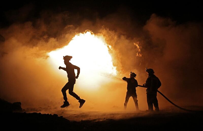 Members of the Syrian Civil Defence fight a fire which erupted after a bombardment of makeshift oil refining installations in the Tarhin area, near the Turkish-controlled city of Al Bab in the north of Aleppo province. AFP