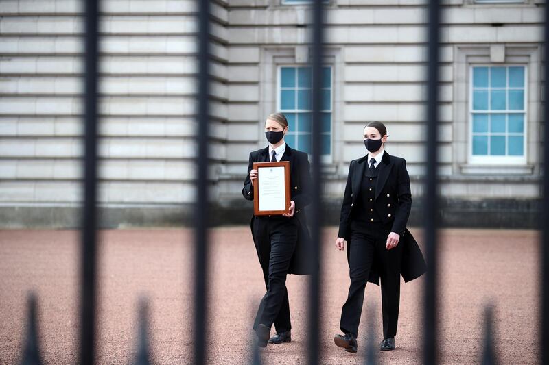 Staff members bring a notice to the fence of Buckingham Palace. Reuters