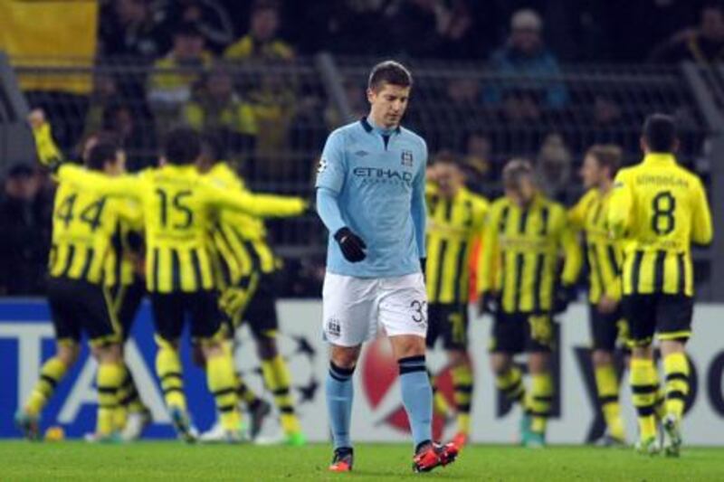 A dejected Matija Nastasic walks off as Borussia Dortmund celebrate their win over Manchester City.