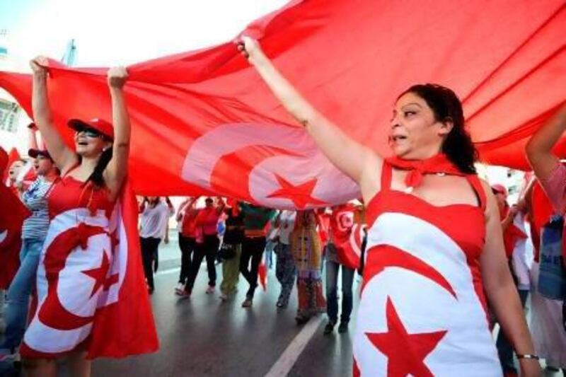 TOPSHOTS - Tunisian demonstrators, bearing the colours of their national flag, shout slogans during a protest against the country's Islamist-led government in front of the Constituent Assembly headquarters in Tunis on August 13, 2013, which marks national women's day, as the president proposed a national unity cabinet to end a protracted crisis. The government, led by the Islamist Ennahda party, and its detractors have been locked in a bitter feud sparked by the July assassination of an opposition politician, the second such killing this year. TOPSHOTS / AFP PHOTO / FETHI BELAID
 *** Local Caption *** 733484-01-08.jpg
