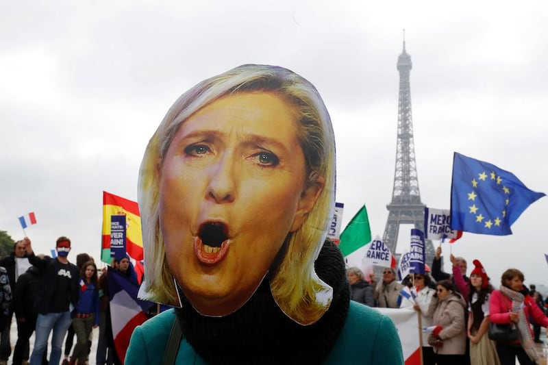 A woman wears a mask depicting the defeated far-right French presidential election candidate Marine Le Pen in front of the Eiffel Tower in Paris on May 8, 2017. Francois Guillot / AFP