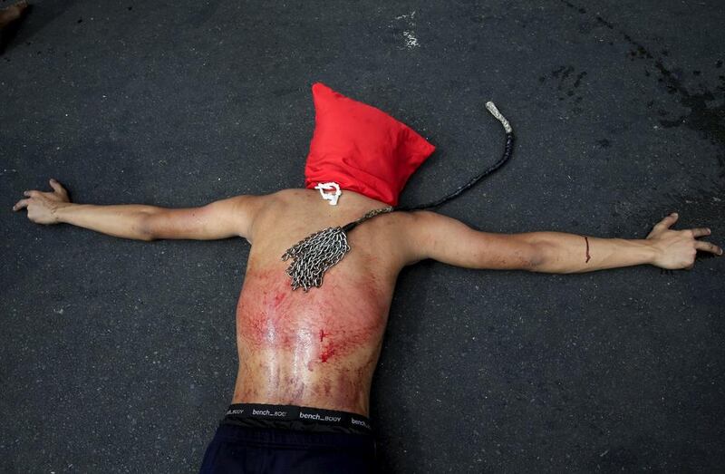 A masked Filipino penitent lies face down on a road while praying after performing self-flagellation, a form of bodily penance to atone for their sins, in Mandaluyong city. Romeo Ranoco / Reuters