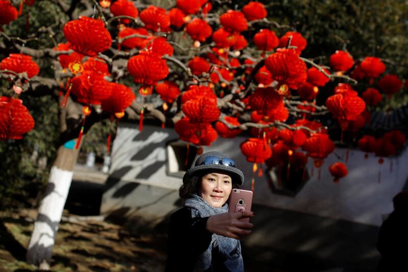 A woman takes a selfie in front of a tree decorated with red lanterns in Ditan Park in Beijing, China. Reuters