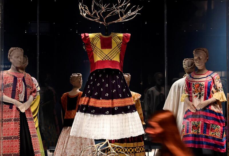 An employee poses as she walks past dresses and tunics forming part of 'Frida Kahlo:Making Herself Up',  an exhibition of the Mexican artist's possessions which goes on display outside of Mexico for the first time, at the Victoria and Albert Museum in London, Britain, June 13, 2018. REUTERS/Toby Melville