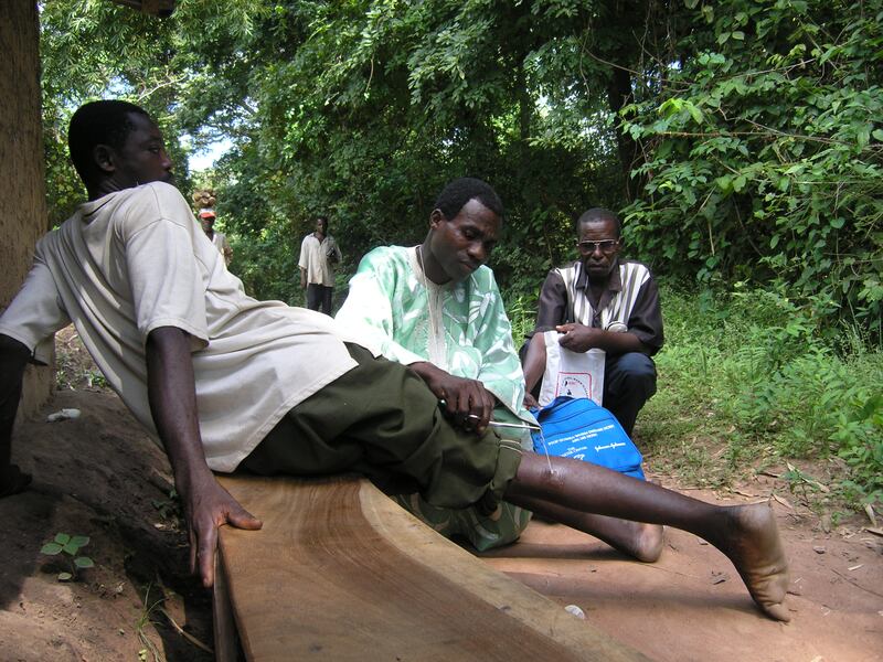 A volunteer in Nigeria inspects a Guinea worm emerging from a man's calf. Guinea worm is on track to become the second human disease, and the first parasitic infection, to be eradicated as cases hit an all-time low.