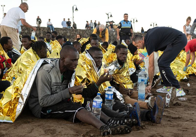 Migrants are fed and wrapped in thermal blankets after arriving at La Garita beach in Arrieta, on the Canary Island of Lanzarote, on December 27. EPA
