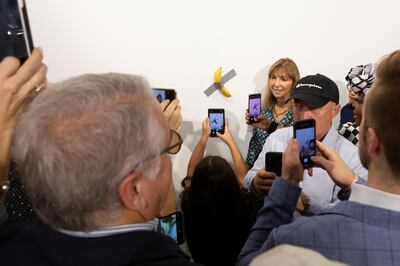 A woman poses for a photo next to a banana attached with duct-tape that replaces the artwork 'Comedian' by the artist Maurizio Cattelan, which was eaten by David Datuna, in Miami Beach, Florida, December 7, 2019.  REUTERS/Eva Marie Uzcategui