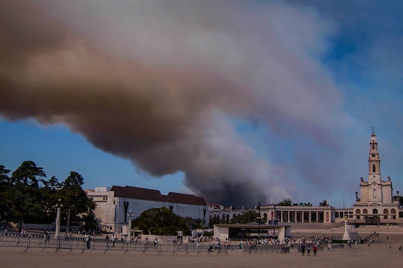 Smoke billows above the Sanctuary of Our Lady of Fatima, after a fire broke out in Fatima, Portugal. AFP
