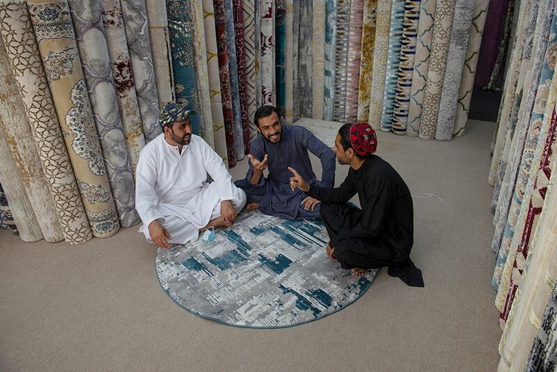 Friends Syed Abbas, Sabir and Aziz Khan, left to right, sit in their carpet shop in Abu Dhabi.