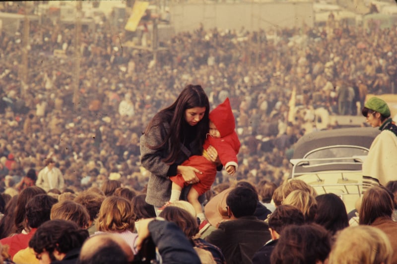 A woman carries a child through the massive audience at the Altamont Speedway in 1969 prior to the free concert headlined by the Rolling Stones. Getty Images