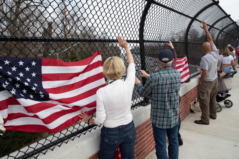 People on an overpass show their support as The People's Convoy, an anti-vaccine mandate truck convoy originating on the west coast, drives by on the outer loop of the Capital Beltway near Washington.
