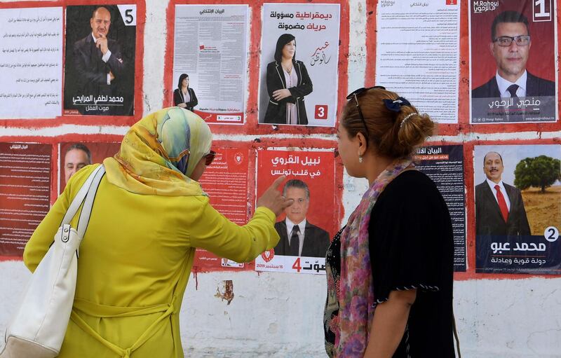 women look at posters of Tunisian presidential candidates in the capital Tunis on September 2, 2019.  Campaigning for Tunisia's presidential elections opened today with 26 candidates vying to replace late leader Beji Caid Essebsi in a vote seen as vital to defending democratic gains in the cradle of the Arab Spring. / AFP / FETHI BELAID

