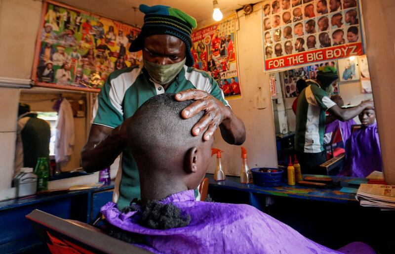 A barber wears a mask while shaving his client in Nairobi, Kenya. Reuters