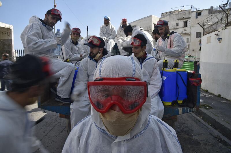 Municipal workers dressed in protective gear rest while on duty disinfecting a street during the COVID-19 coronavirus pandemic in the Bab el-Oued district of Algeria's capital Algiers on April 9, 2020.  / AFP / RYAD KRAMDI
