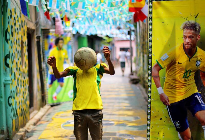 A football fan shows his skills next to a poster of Brazil's Neymar in a lane decorated with Brazilian flags and painted walls at the Sonagachi district in Kolkata, eastern India. Piyal Adhikary / EPA