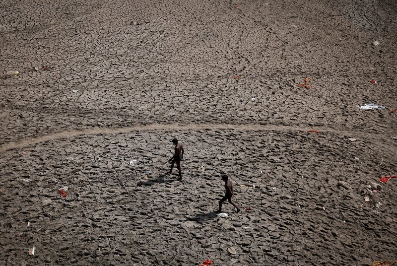Men walk over the bed of the Yamuna River in search of recyclable material in New Delhi. Reuters