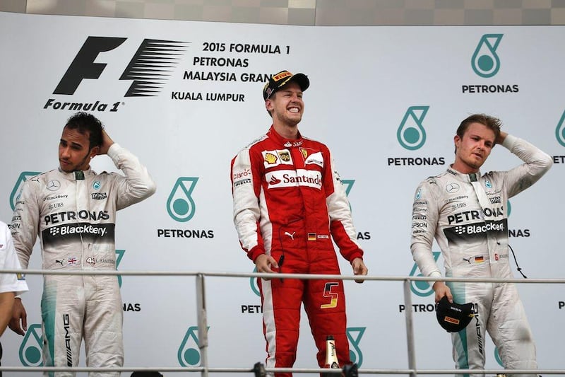 An elated Sebastian Vettel, centre, tops the Malaysian Grand Prix podium, while Mercedes duo Lewis Hamilton, left, and Nico Rosberg, right, look on. Vincent Thian / AP Photo