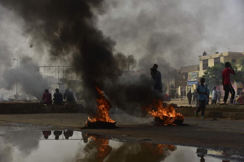 Sudanese protesters walk past burning tyres during a demonstration in Khartoum's twin city of Omdurman. AFP