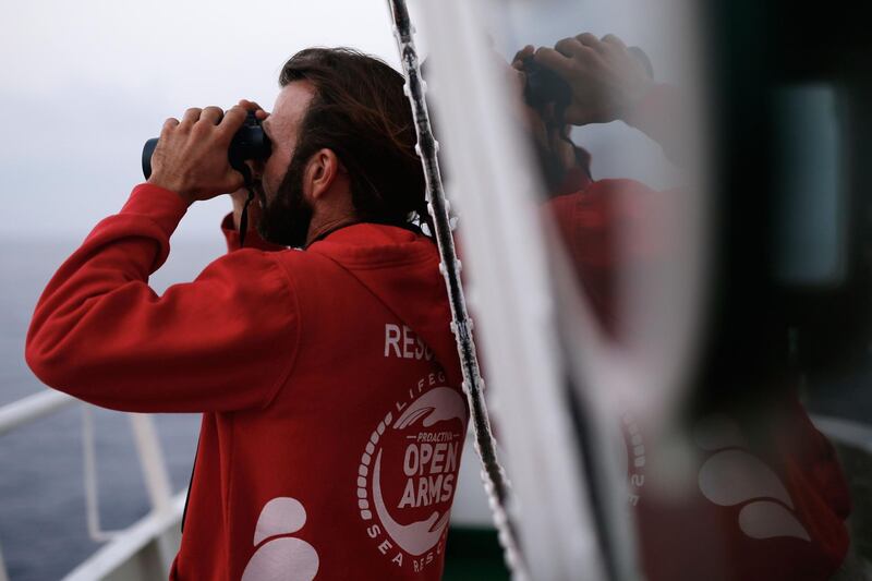 Spanish member of the Spanish NGO Proactiva Open Arms Jose Medina ises his binoculars as he searches for a rubber boat after a distress call on board of the Proactiva Open Arms rescue vessel in the Mediterranean open sea about 80 miles of the Libyan coast on July 17, 2018. / AFP / PAU BARRENA
