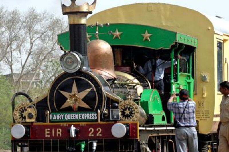 Local commuters, with their belongings, sit on a railway platform in front of the Fairy Queen engine, the world's oldest working locomotive, in the desert Indian state of Rajasthan March 28, 2010. The locomotive was built in 1855 by the British firm Kitson, Thompson and Hewitson for the East Indian Railway (EIR). REUTERS/Vijay Mathur (INDIA - Tags: TRAVEL SOCIETY TRANSPORT)