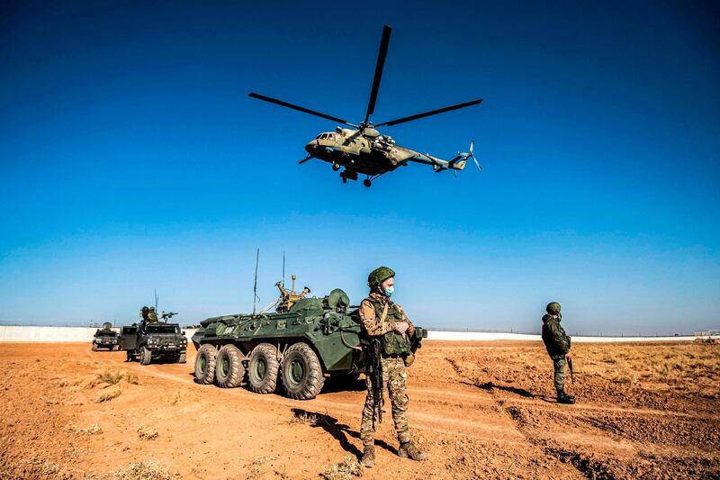 A Russian Mi-17 military helicopter flies by soldiers and military vehicles during a joint Russian-Turkish patrol in Darbasiyah near the border with Turkey in Syria's northeastern Hasakah province.  AFP