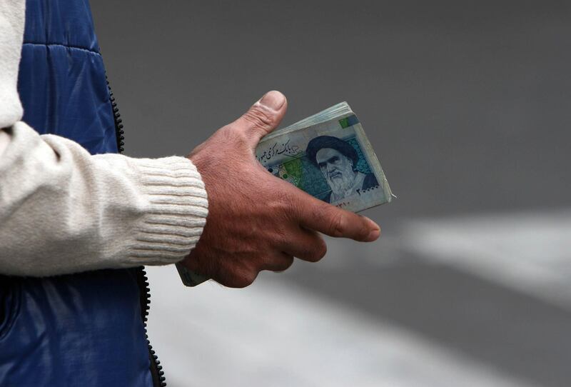 FILE - In this Thursday, Oct. 30, 2008 file photo, an Iranian money changer holds currency with Ayatollah Ruhollah Khomeini's image in Tehran, Iran. Iranâ€™s currency on Saturday, June 20, 2020 has dropped to its lowest value ever at 190,000 rial for each dollar amid severe U.S. sanctions against the country.(AP Photo/Hasan Sarbakhshian, File)