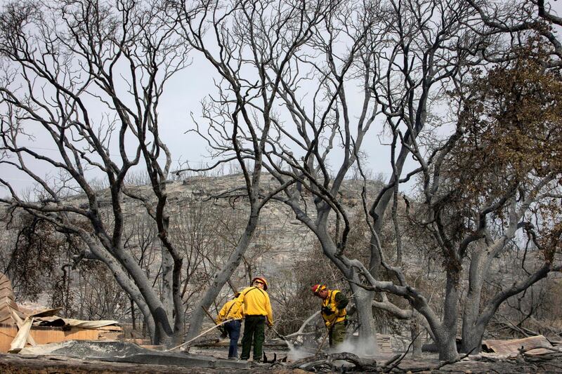 Firefighters soak the smoldering ground on the coast of Possum Kingdom Lake in Graford, Texas. AP