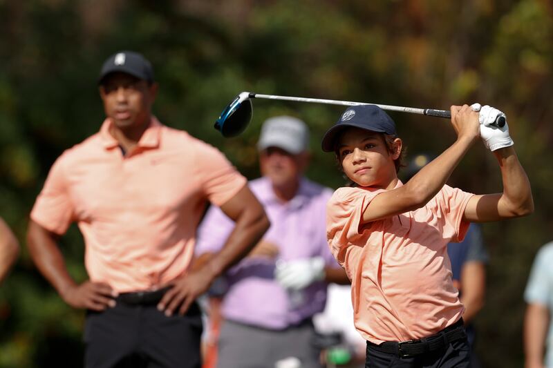 Charlie Woods tees off while being watched by father Tiger Woods on the first tee during the first round of the PNC Championship golf tournament Saturday, December 18, 2021, in Orlando. AP
