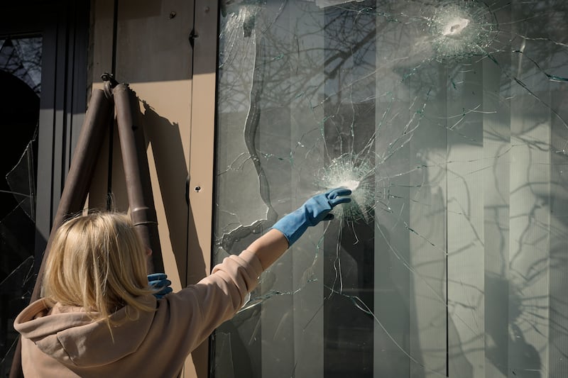 A woman removes pieces of broken glass from a shop window after a bombing in Kyiv, Ukraine. AP