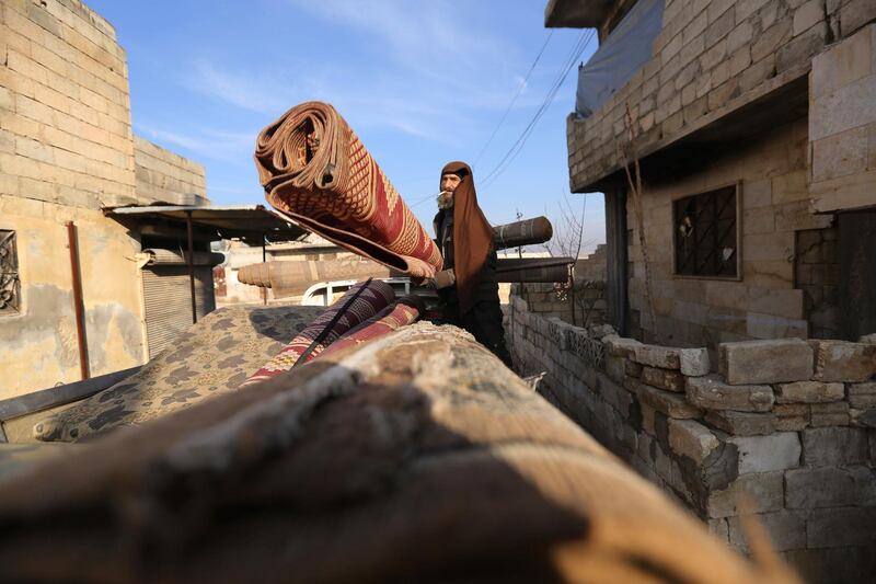 A man loads floor mats onto a truck as civilians flee Maaret Al Numan, Syria. AP Photo