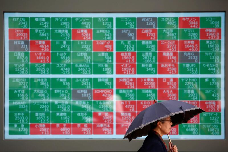 A passerby walks past in front of a stock quotation board outside a brokerage in Tokyo, Japan. Reuters