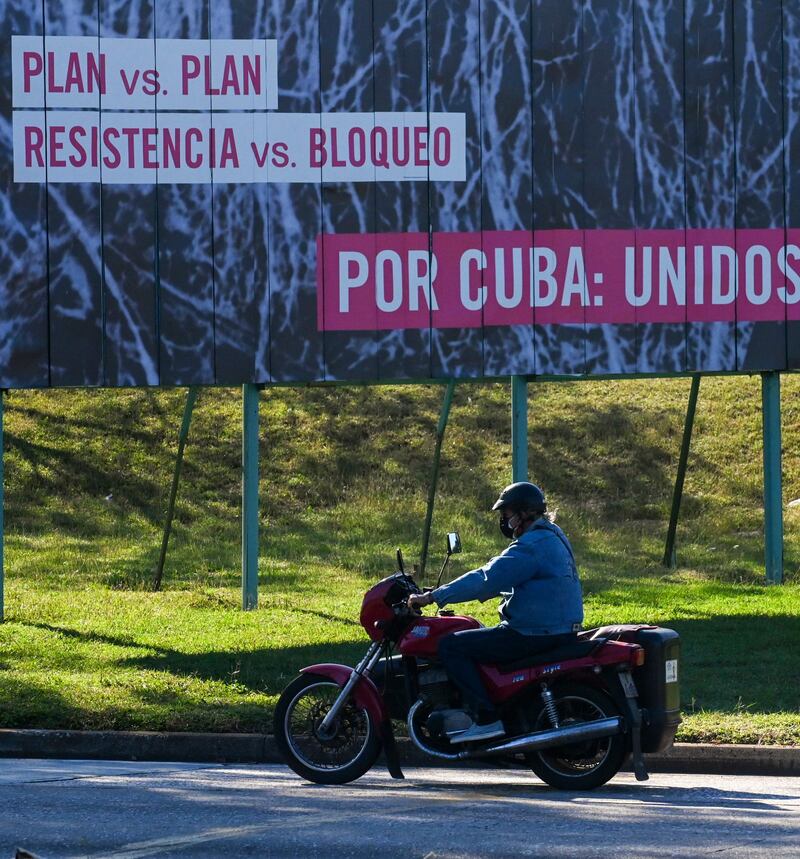 A man rides his motorcycle near a banner reading 'Plan v plan. Resistance v blockade. For Cuba: United' in Havana. AFP