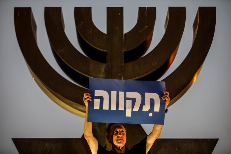 A supporter of the coalition government holds a placard that reads in Hebrew "Hope". Reuters