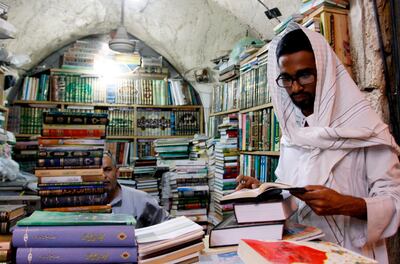 A religious student pages a book at the Howeish book market in the holy city of Najaf, 150 kilometres (95 miles) south of Baghdad, on August 16, 2018.   
 In the covered alleyways of old Najaf in Iraq, poetry and philosophy books compete with economic treatises, the Koran and other theological tomes for students' attention. / AFP / Haidar HAMDANI
