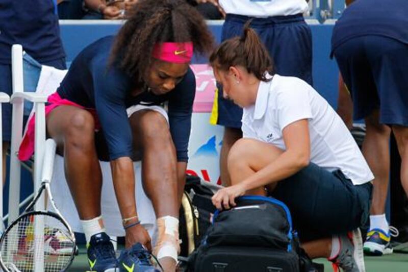Serena Williams receives treatment on her ankle from a trainer during her doubles match at the US Open.