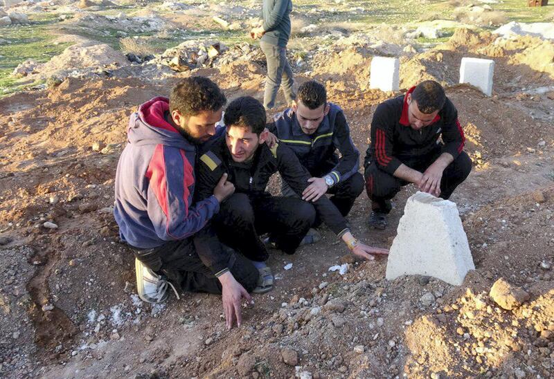 IDLIB, SYRIA - APRIL 6: Abdel Hameed Alyousef (2nd L) mourns over his wife and twin babies, killed in the chemical attack by Assad Regime, at their cemetery in Idlib, Syria on April 6, 2017. Abdel Hameed Alyousef lost his wife and 9 month old twin babies named Aya and Ahmad in addition to 13 of his family members in the chemical attack. The grief-stricken father said: " Dear God took Ahmad and Aya, I am not upset over this. Gulf countries do not deliver an international society which they speak of. We will be patient until the last day and the victory will come. We are not the first nor the last. Our children have been dying in our hands for 6 years. No one seems to help." Assad Regime struck Khan Shaykhun district of Idlib in Syria with a chemical weapon leaving at least 100 civilians, including women and children, dead and at 500 affected from the gas. 

 (Photo by Mohammed Al Daher/Anadolu Agency/Getty Images)