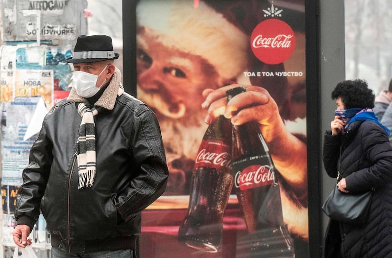 A man wears a protective mask as he stands in front of a billboard  in Skopje, Macedonia Robert Atanasovski / AFP Photo