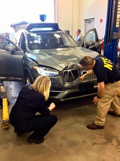 FILE - In this March 20, 2018, file photo provided by the National Transportation Safety Board, investigators examine a driverless Uber SUV that fatally struck a woman in Tempe, Ariz. A prosecutor has determined that Uber is not criminally liable in the crash that killed 49-year-old Elaine Herzberg. (National Transportation Safety Board via AP, File)