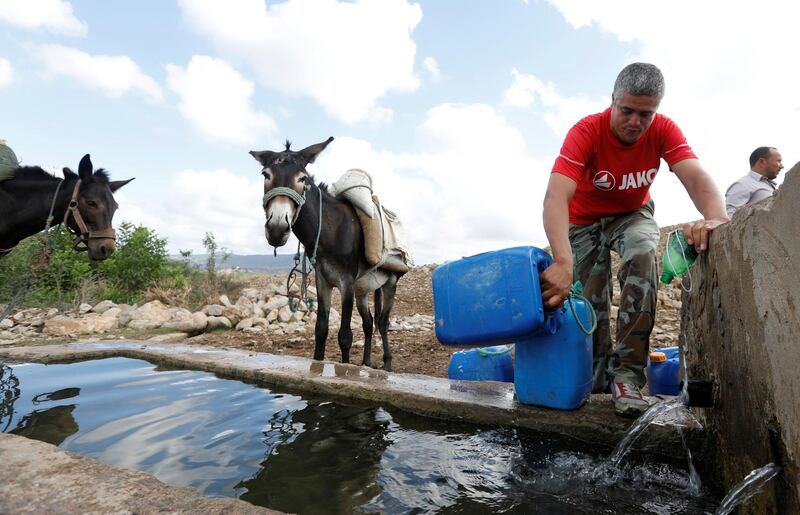 A man fills containers with water from a well, which are transported home on his donkey in Oued al-Berber, Tunisia.  Reuters