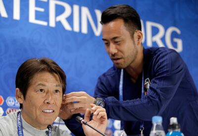 Japan's Maya Yoshida, right, helps place a head set to the ear of Japan's head coach Akira Nishino during a press conference on the eve of the group H match between Japan and Senegal at the 2018 soccer World Cup in the Yekaterinburg Arena in Yekaterinburg, Russia, Saturday, June 23, 2018. (AP Photo/Mark Baker)