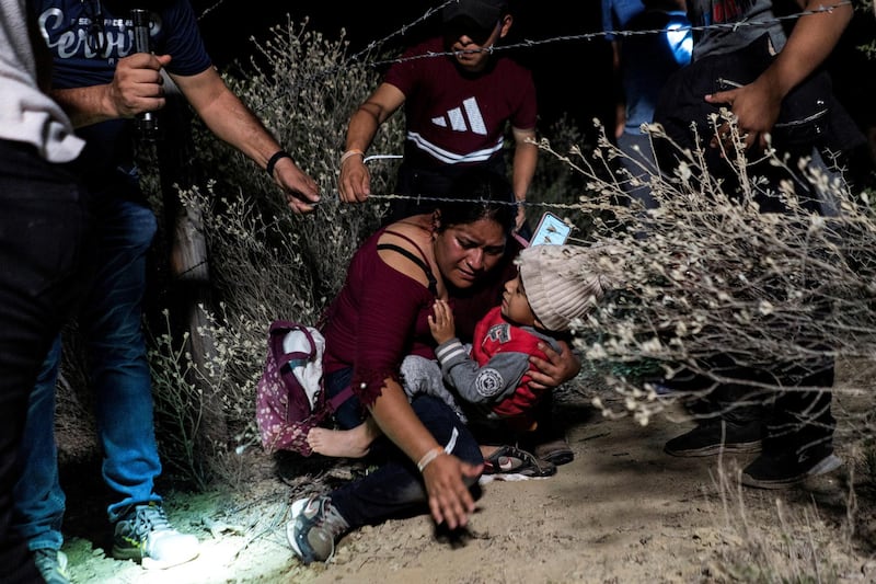 Families of migrants go under a barbed-wire fence while being escorted by a local church group to the location where they turn themselves in to the US Border Patrol in the hope of securing asylum, after crossing the Rio Grande river into the US from Mexico, in Roma, Texas. Reuters