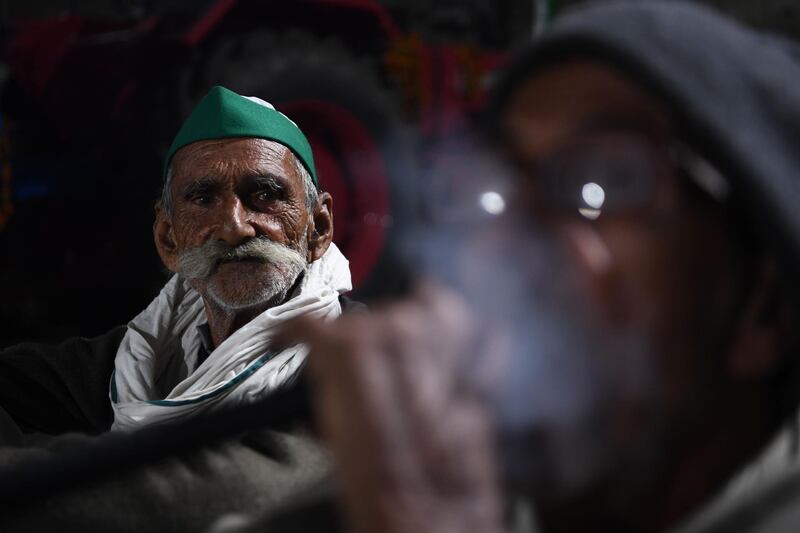 Farmers smoke a water pipe while resting under a bridge near a police road block stopping them from marching to New Delhi to protest against the central government's recent agricultural reforms.  AFP