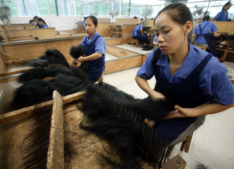 Assembly line workers craft the wigs with precision. AFP