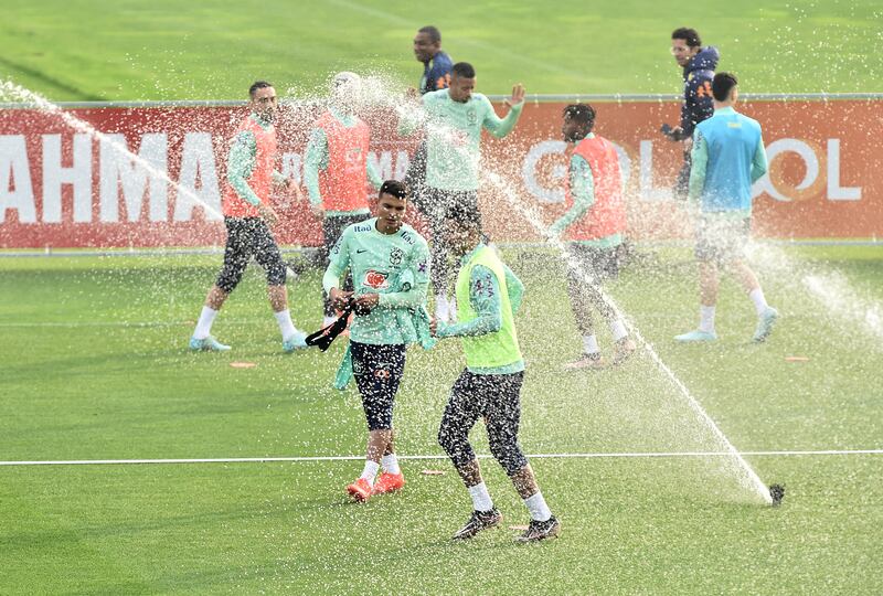 Brazil's Thiago Silva with teammates as the sprinklers go off during training. Reuters